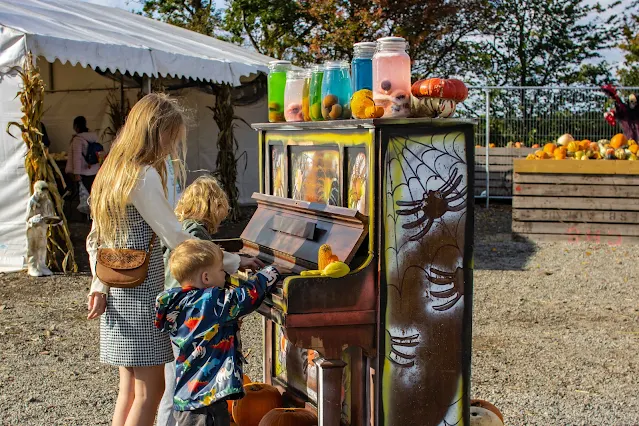 3 children standing next to a halloween themed piano at a pumpkin patch