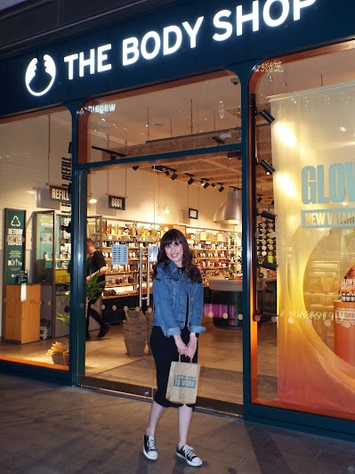 Blogger, Megan Goodier, posed with a cheerful smile outside the warmly lit Body Shop Liverpool One.