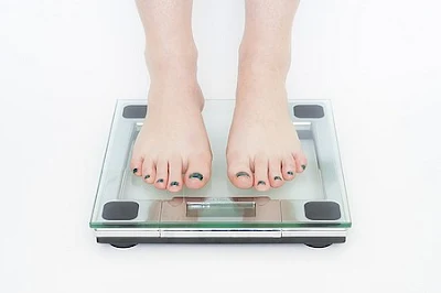 standing on a scale with a weight loss plateau