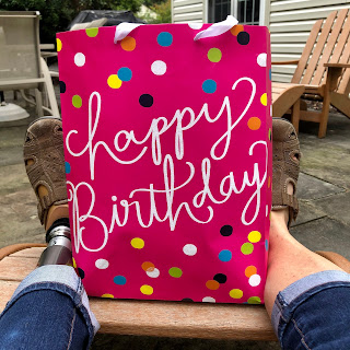 My feet with a happy birthday bag between them.