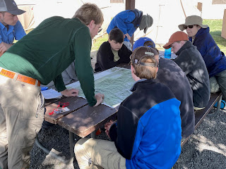 A picture of Scouts reviewing a map on a picnic table.