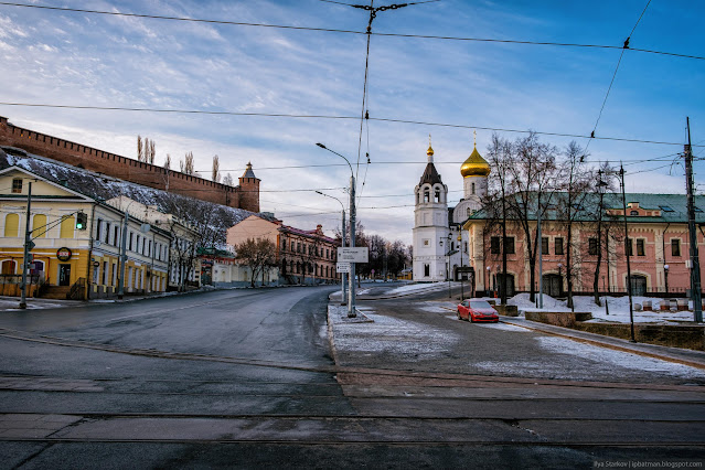 Дорога между старыми домами и церковью, а на фоне стены кремля