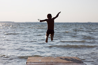 Силует хлопця в повітрі під час стрибка в озеро Світязь.