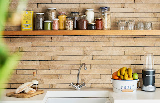a kitchen sink with jars of food on a shelf above it