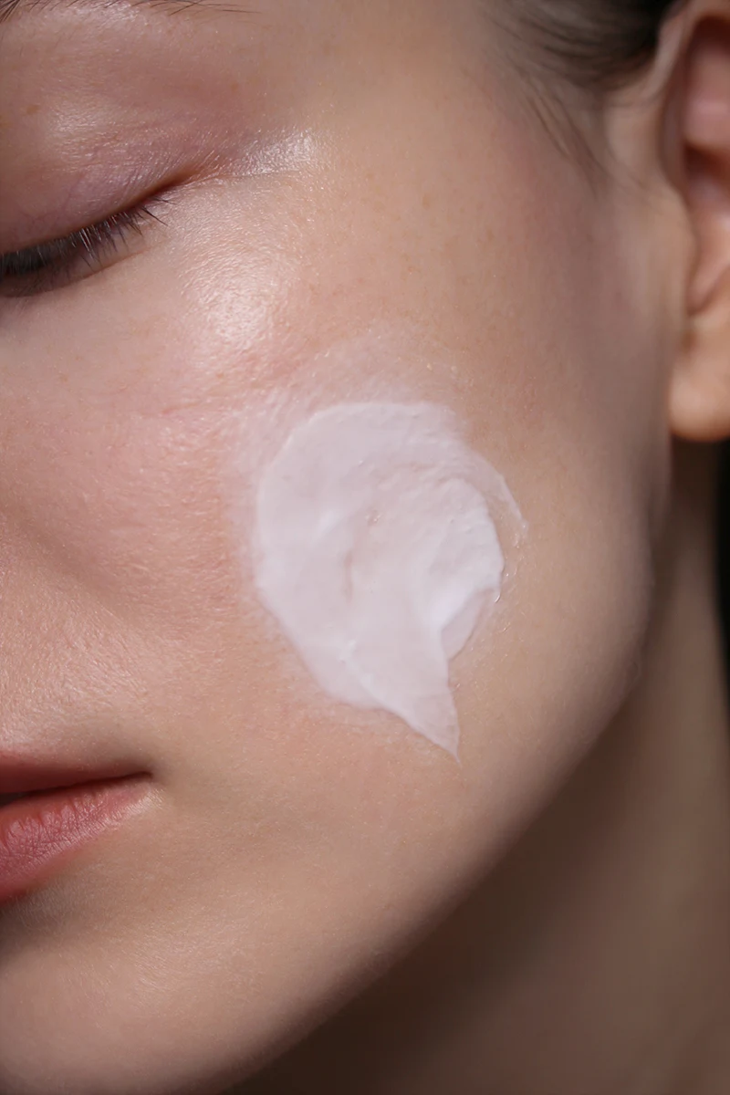 close-up shot of females face with a smudged moisturizer on a cheek