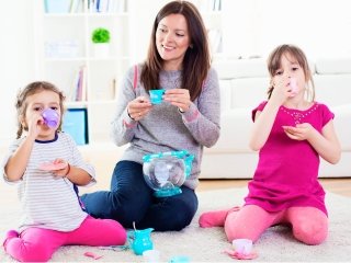 A mother having a pretend play indoor tea party with her two daughters