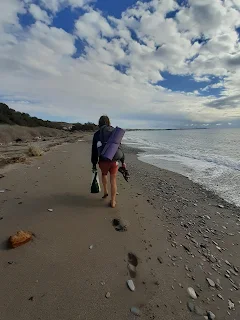 I walk through soft sand along the water at a beach