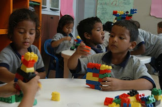 Niños y niñas jugando con piezas de construcción en un aula