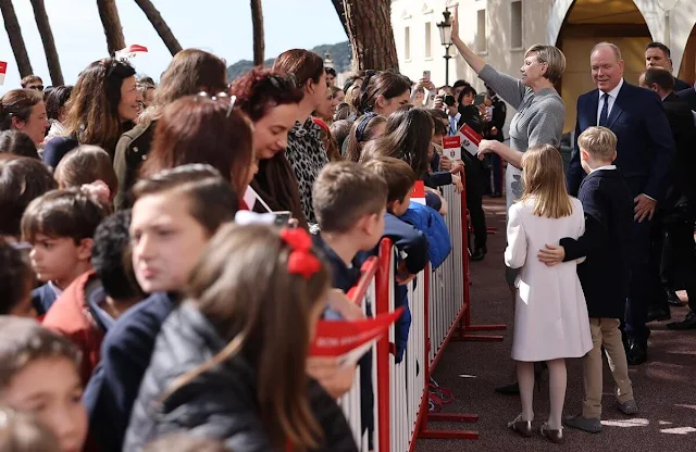 Princess Charlene wore a grey solid v-neck knitted dress by Akris. Princess Gabriella wore a white coat by Burberry