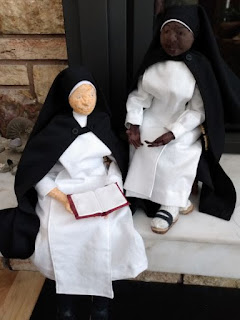 Two cloth doll nuns sitting on a fireplace mantlepiece