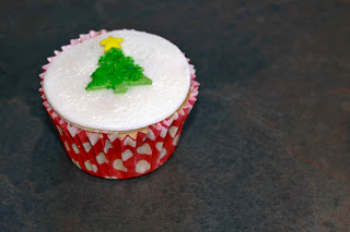 Christmas cupcake topped with marzipan and icing, with a sparkly Christmas tree decoration