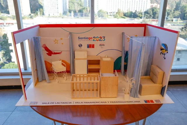 Representação em maquete da sala. Ela está em tons claros de madeira e há um berço, armário e duas salas privativas para amamentação