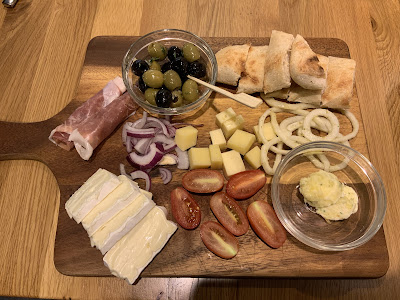 Photo of platter with ham, olives, cheese, bread, and suchlike.