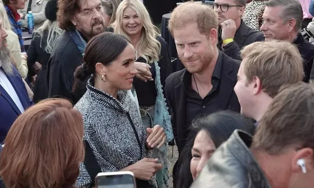 Meghan Markle, Duchess of Sussex wore a black and ivory oversized tweed cape by Carolina Herrera. Actor Kevin Costner