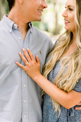 girl showing off engagement ring with hand on fiances chest
