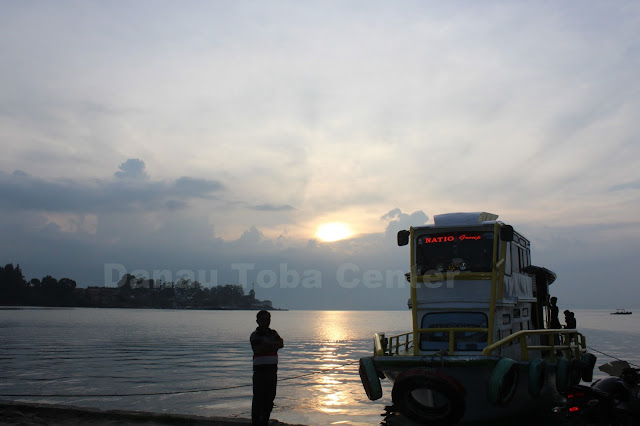 Seorang laki-laki menyaksikan terbenamnya Matahari di Danau Toba, dengan kapal motor penumpang di pelabuhan Danau Toba Parapat.  (photo: tagor)