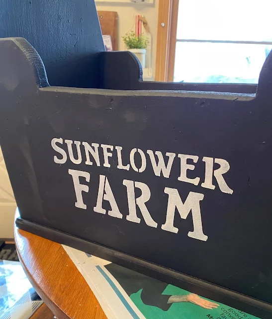 Photo the front of tool tote painted with black chalk paint & stenciled with "Sunflower Farm".