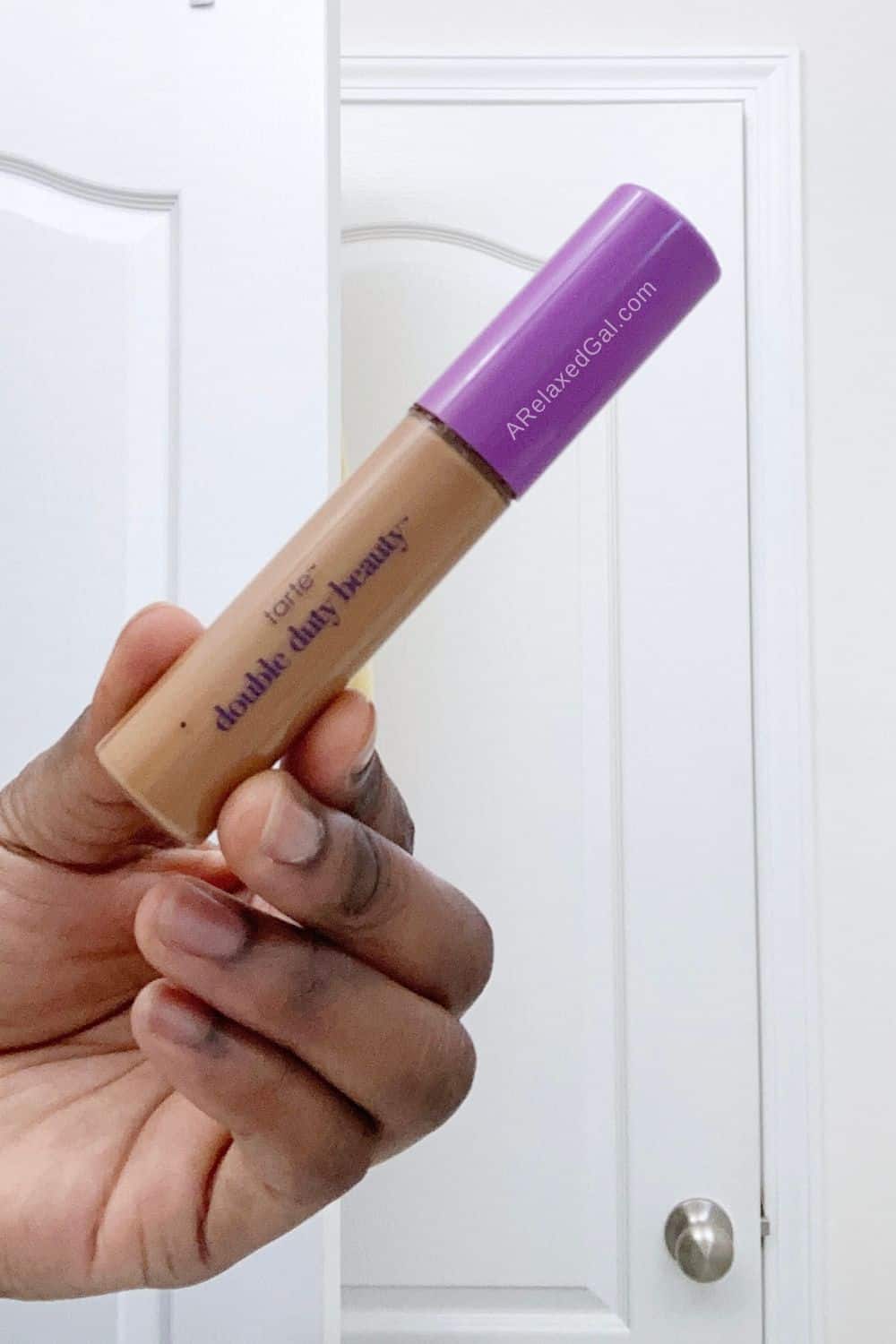 black woman holding a tube of the tarte shape tape concealer