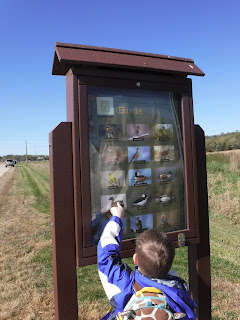 a boy points at a sign featuring pictures of animals at Prairie Park in Sioux City