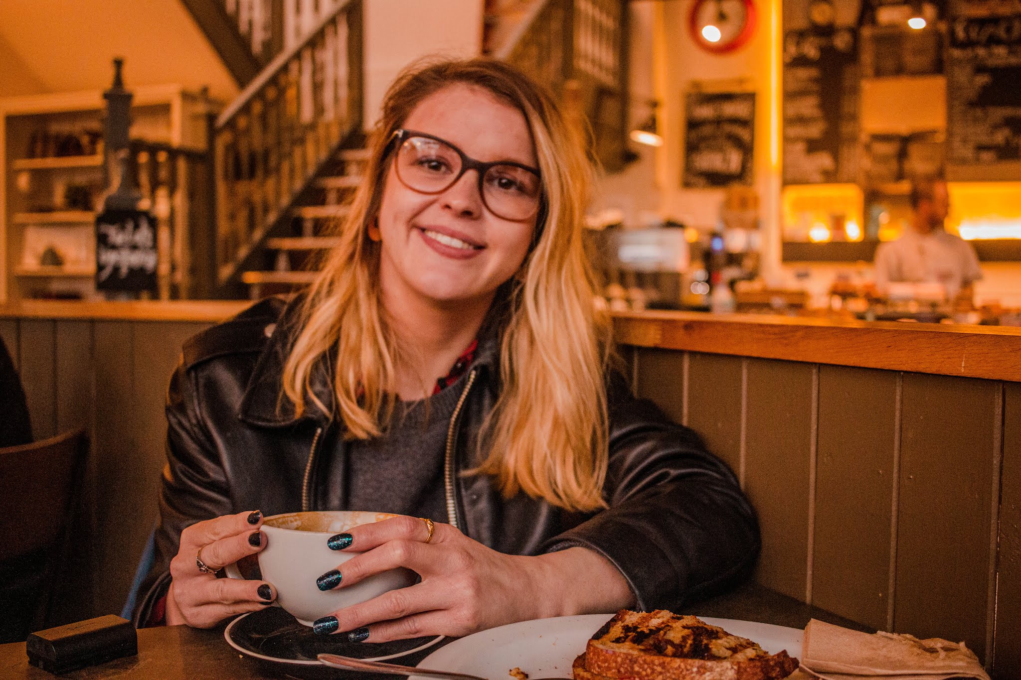 blonde girl chloeharriets in leather jacket and thick rimmed glasses, in coffee shop smiling for lifestyle blog picture, new year new start, blog rebrand