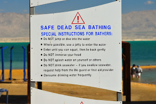 sign with instructions for swimming bathing in dead sea at en bokek beach