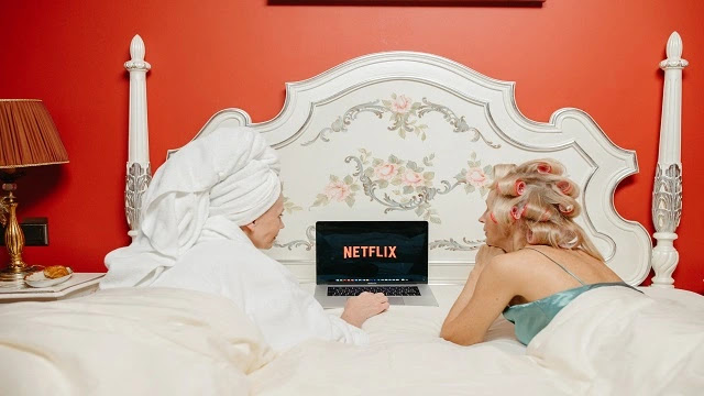 Two ladies browsing Netflix on the bed