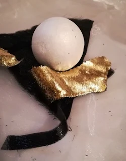 un glob alb din polistiren si doua bucati mici de material lucios: unul auriu, unul negru