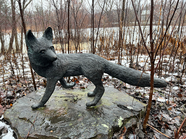 Fox sculpture along a trail with a view of the tear drop pond.