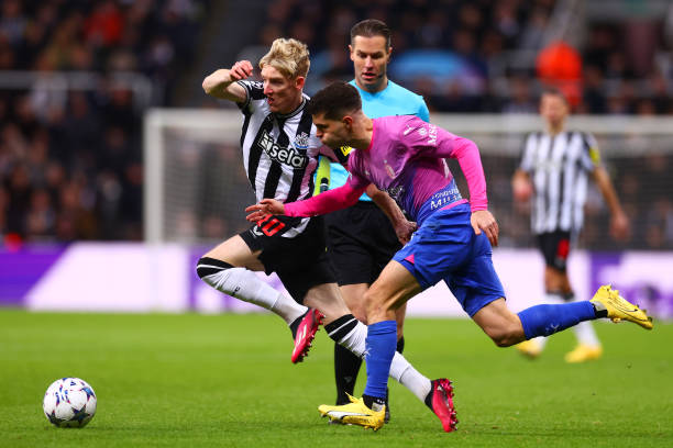 Anthony Gordon of Newcastle United in action with Christian Pulisic of AC Milan during the UEFA Champions League match between Newcastle United FC and AC Milan at St. James Park on December 13, 2023 in Newcastle upon Tyne, England.