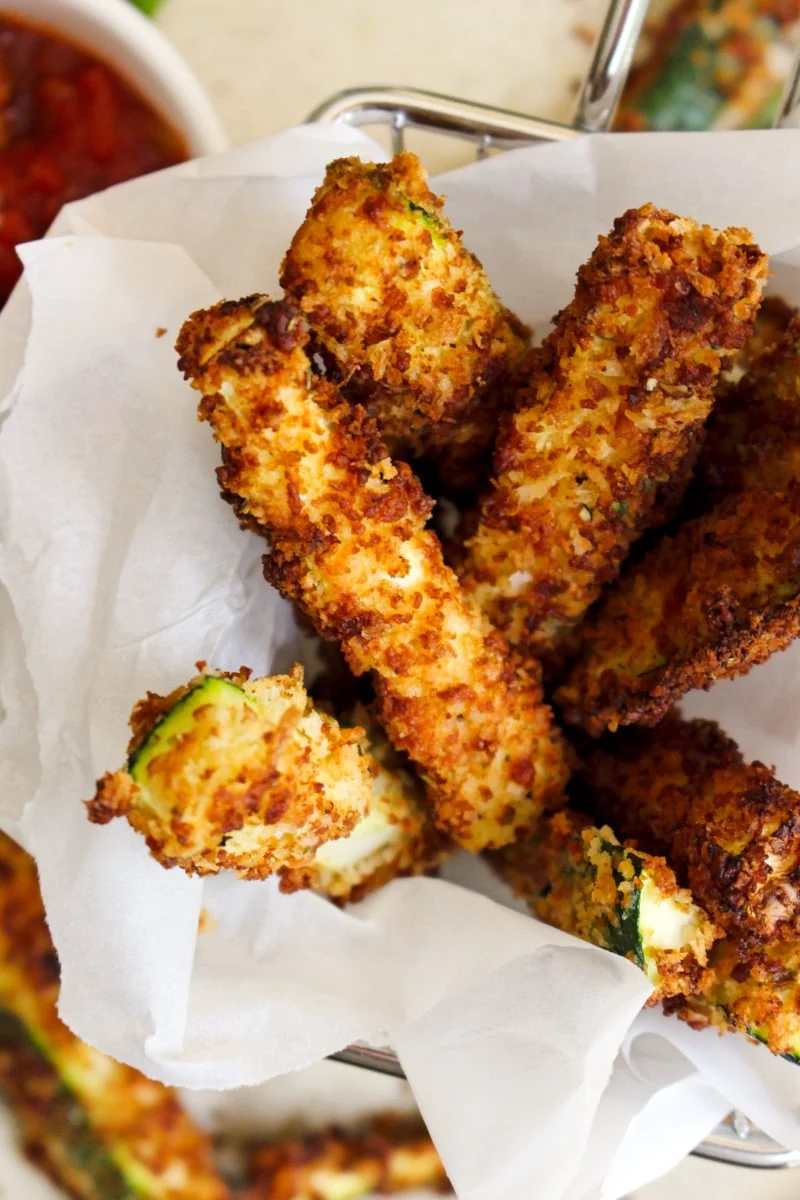 Air Fryer Zucchini Fries in a parchment paper-lined metal basket.