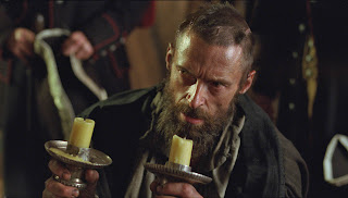 Hugh Jackman sosteniendo dos candelabros en la película de Los miserables (2012)