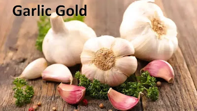 Fresh garlic bulbs and cloves with herbs on a wooden surface.