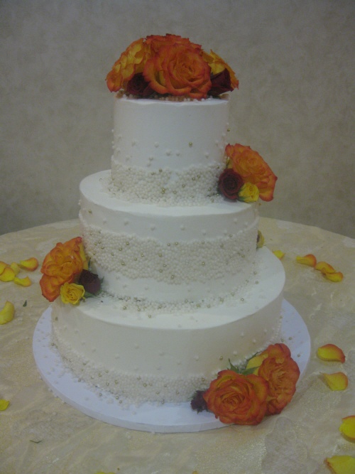 Three tier round wedding cake with fresh roses in burgundy 