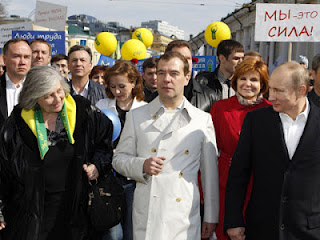 Medvedev, center, and Putin, right, at a May Day rally, in his white raincoat