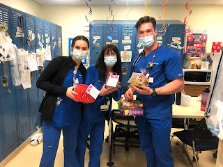 Three nurses, Deb in center, holding cookies.