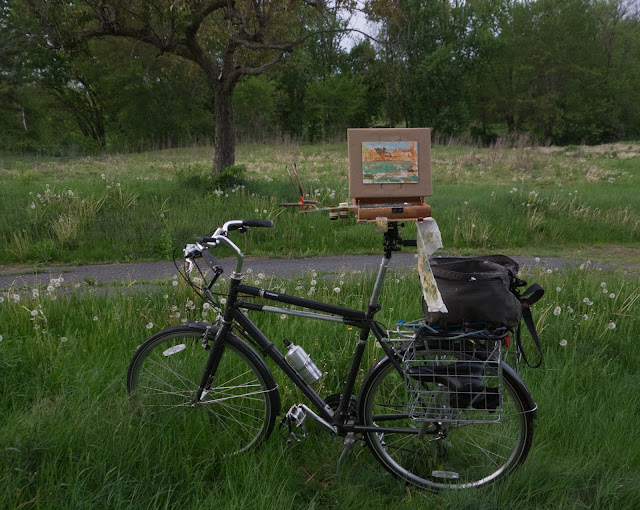 Bicycle with paintbox and partially completed painting mounted on seat post