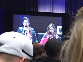 Photo past heads of a giant screen showing David Tennant and Billie Piper on stage.