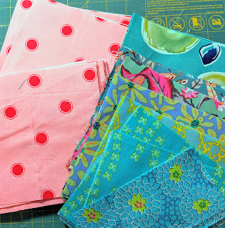 Several turquoise print choices next to a pink fabric with large red polka dots