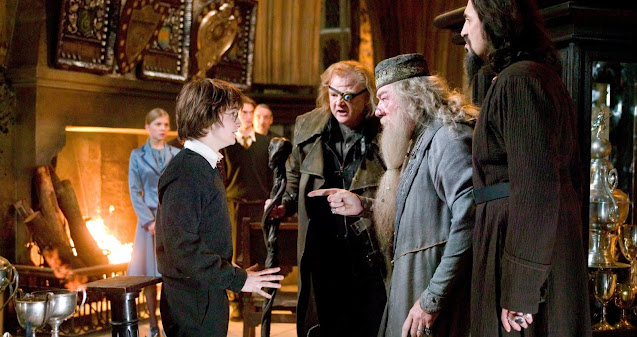Dumbledore is talking with Harry Potter and Alestor Moody and some people looking at them.