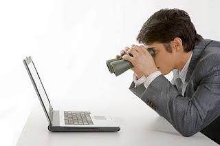 LOOKING AT LAPTOP WITH BINOCULARS