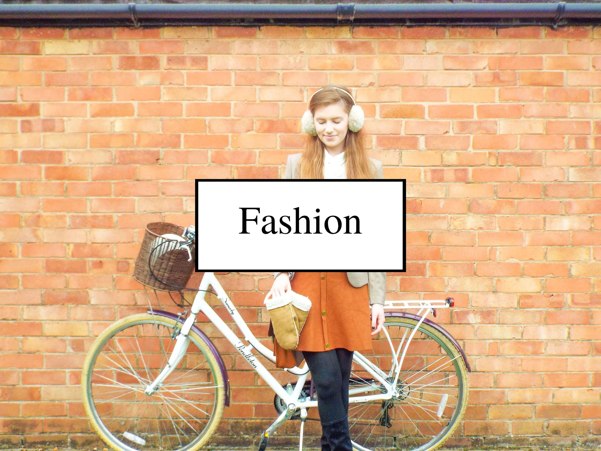 Ellie, stood with her Victoria Pendleton bike against brick wall. Wearing tweed blazer, brown skirt, white shirt, black tights, high leg boots, fluffy ear muffs and mittens.