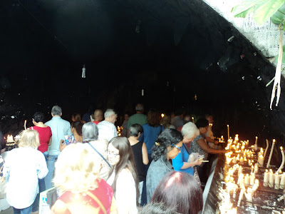 Devotos acendendo velas e orando na gruta