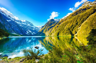a lake surrounded by snowcapped mountains and verdant green hills