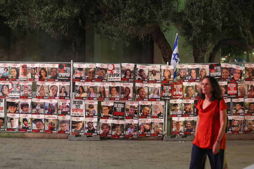 Uma mulher passa por retratos de israelenses feitos reféns por terroristas palestinos no ataque de 7 de outubro, durante uma manifestação pedindo a libertação deles em Tel Aviv, em 13 de novembro de 2023 | Ahmad Gharabli/AFP