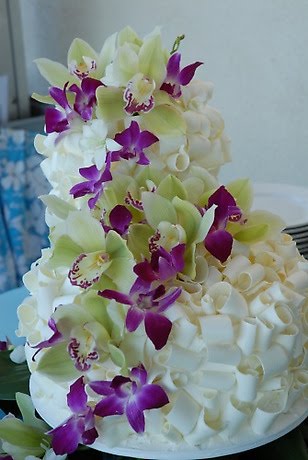 Three tier white chocolate shavings wedding cake decorated with purple 