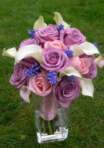 Purple roses with a few pink roses white calla lilies and little blue 