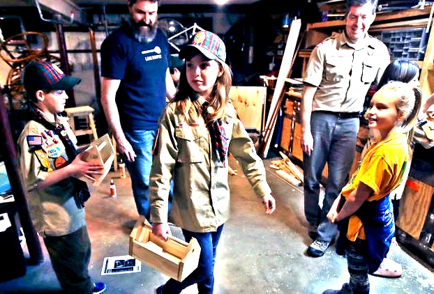 In this March 1, 2018 photo, Tatum Weir, center, carries a tool box she built as her twin brother Ian, left, follows after a Cub Scout meeting in Madbury, N.H.