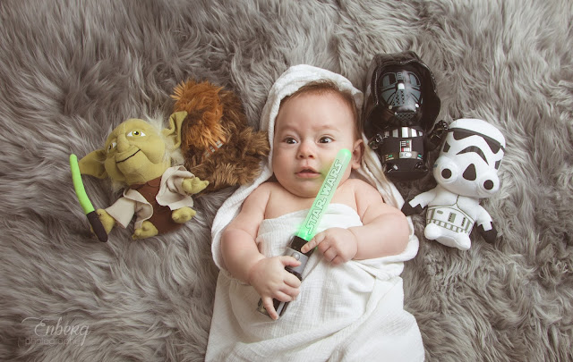 newborn baby boy photographed by Enberg Photography as a Star Wars Jedi with light saber on grey fur rug