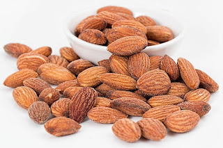 roasted almonds inside and surrounding a white ceramic bowl
