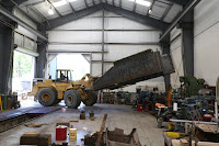 Large loader lifts new tender tank from floor in Conservation and Restoration Center.